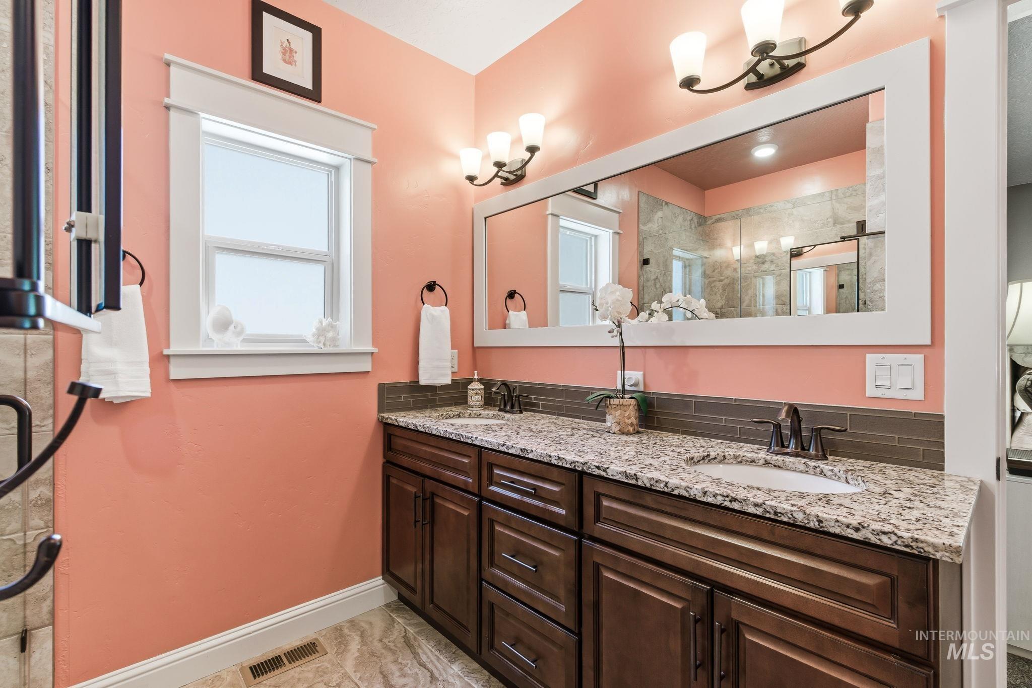 Bathroom featuring a double vanity with granite countertops, undermount sinks, and dark wood cabinetry