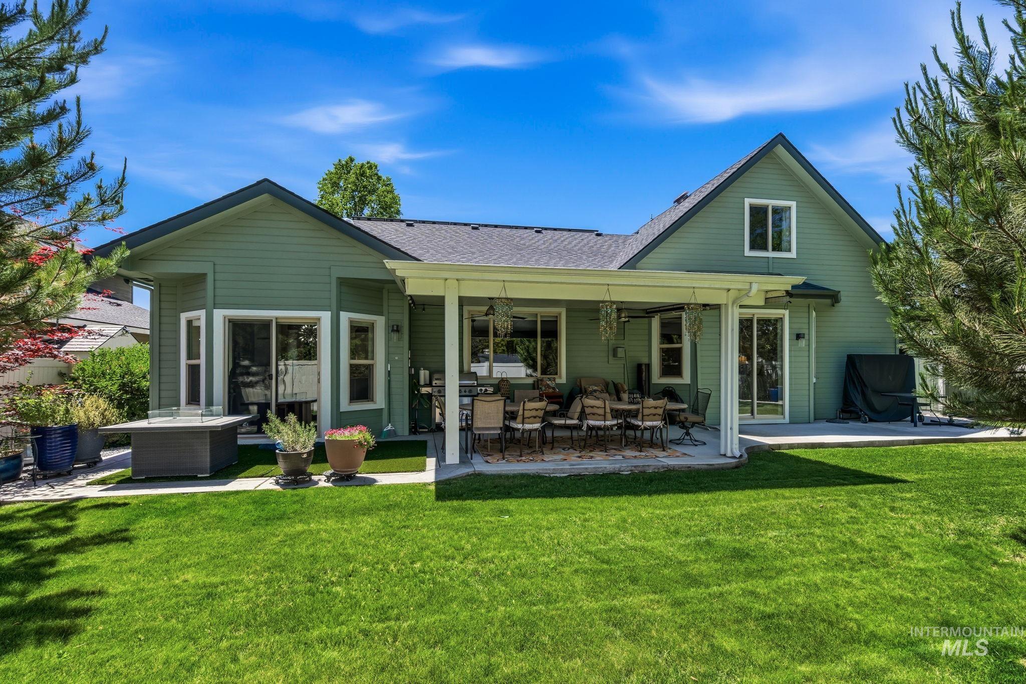 Expansive backyard featuring a covered patio, additional patio space, and a manicured lawn
