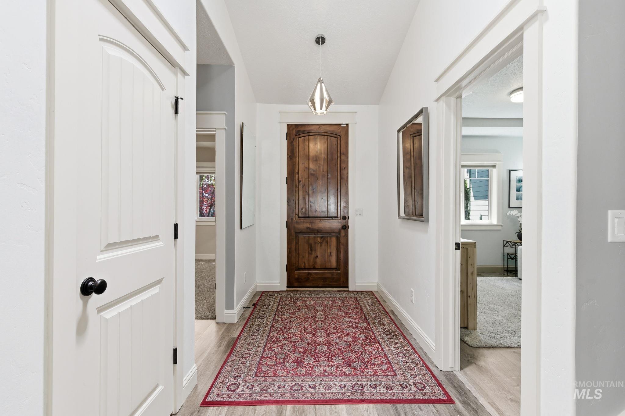 Entryway featuring a wood-finish door, light wood-finish flooring, and white trim