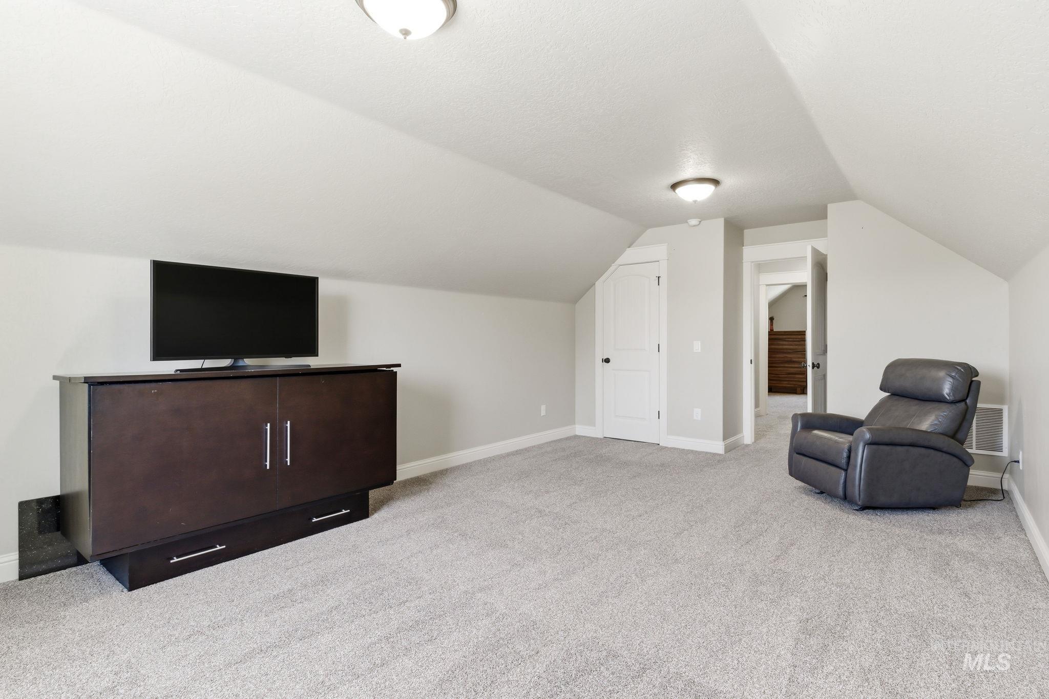 Carpeted bonus room featuring sloped ceilings, two panel doors, and flush mount lighting