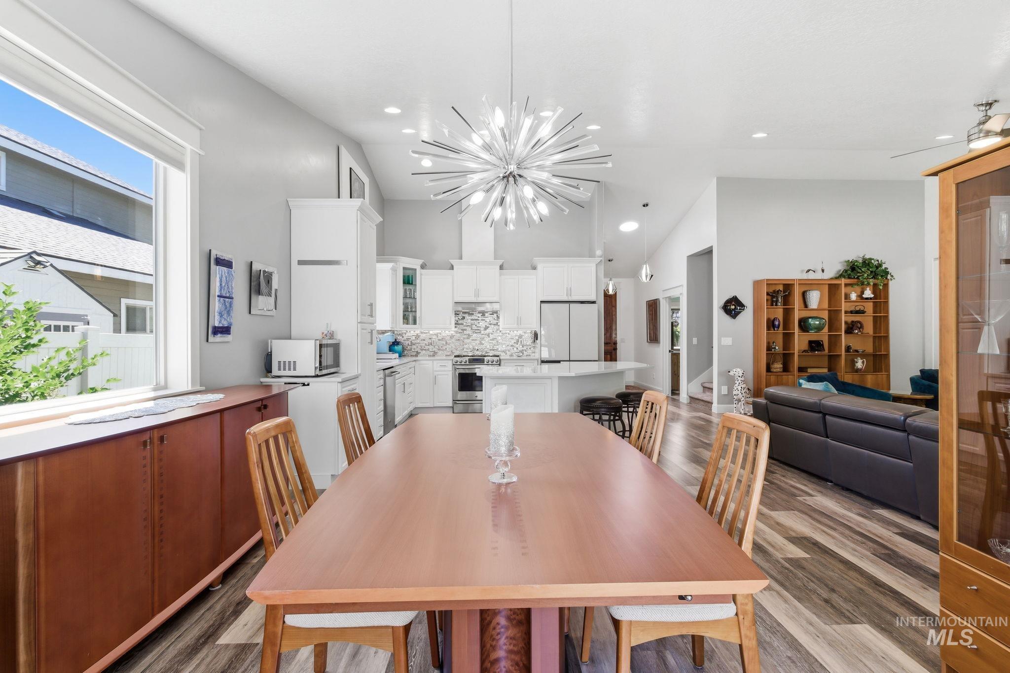 Open-concept living space featuring vaulted ceilings, a contemporary chandelier, and wood-finish flooring