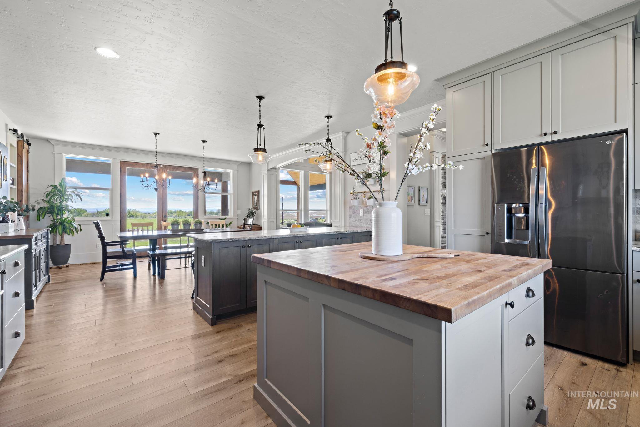 Kitchen with refrigerator with ice dispenser, hanging light fixtures, a chandelier, light wood finished floors, and plenty of natural light