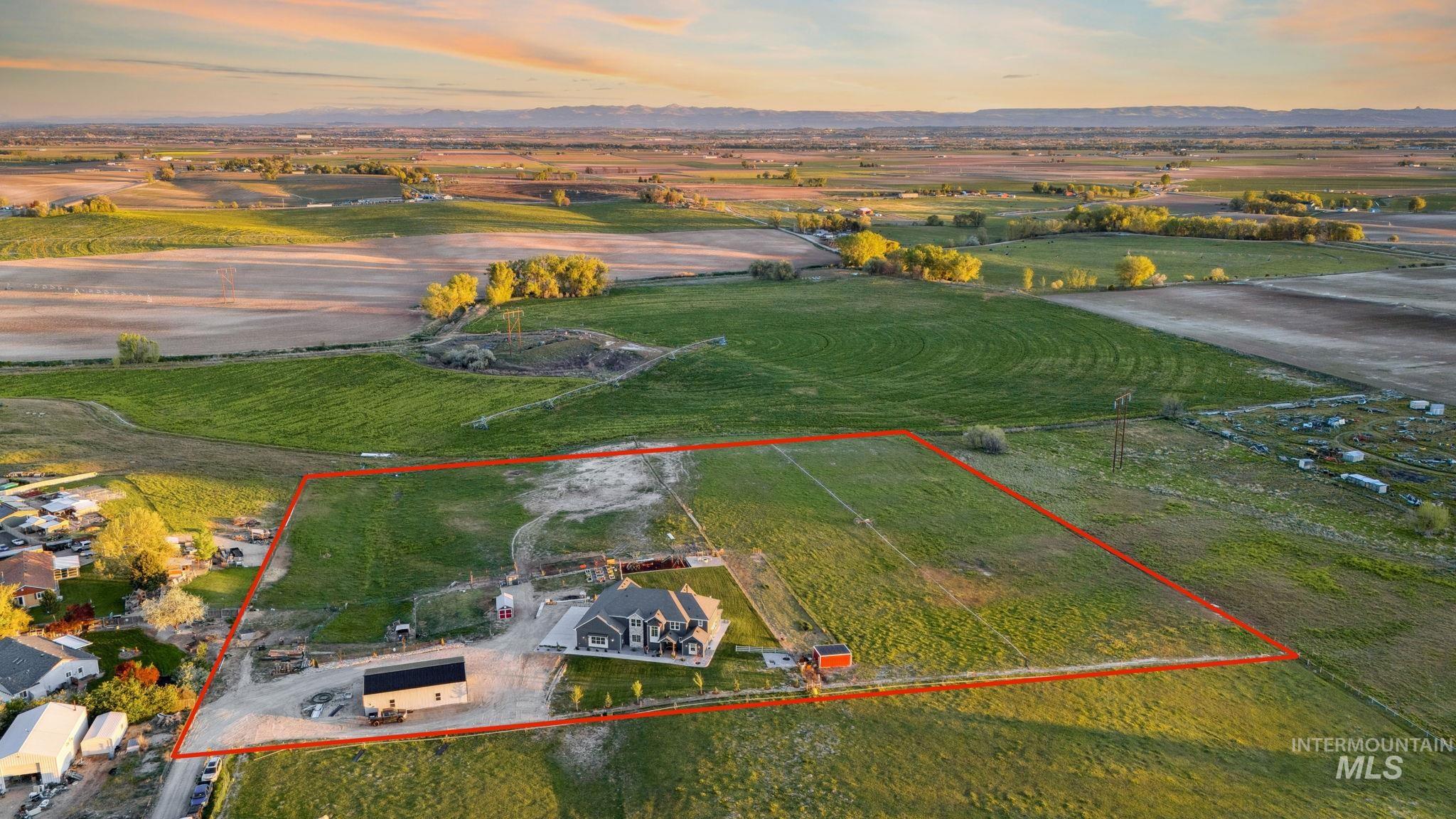 Aerial view of sparsely populated area with property parcel outlined and a mountainous background