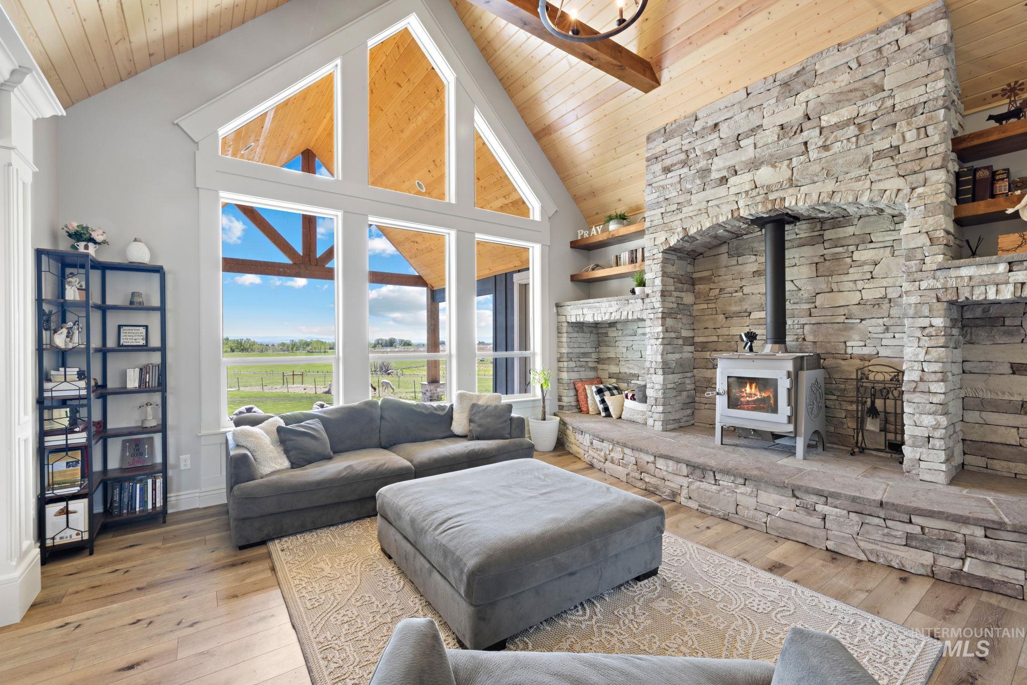 Living area featuring high vaulted ceiling, wooden ceiling, hardwood / wood-style flooring, and a wood stove
