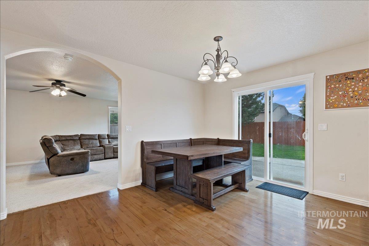 Unfurnished dining area featuring light wood-type flooring, a textured ceiling, plenty of natural light, ceiling fan, and arched walkways