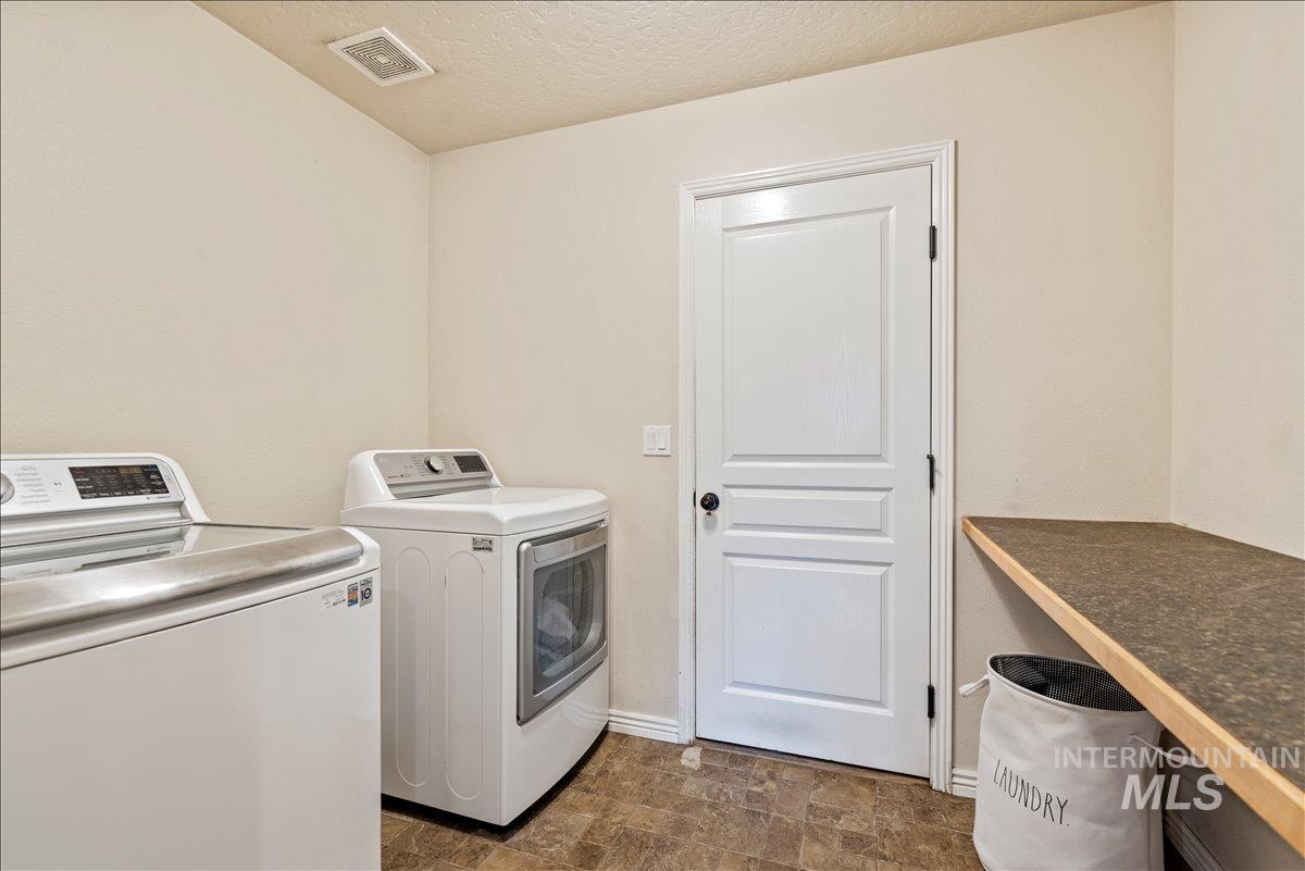 Washroom featuring stone finish floors, washer and clothes dryer, and a textured ceiling