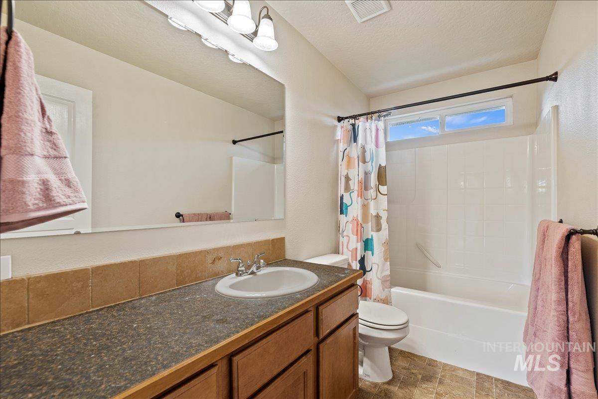 Bathroom featuring shower / bath combo, vanity, and a textured ceiling
