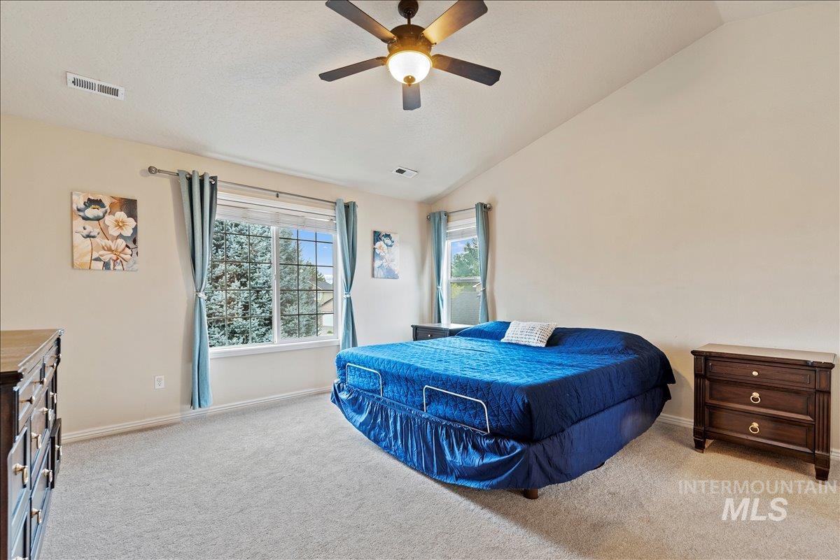Carpeted bedroom featuring vaulted ceiling and ceiling fan