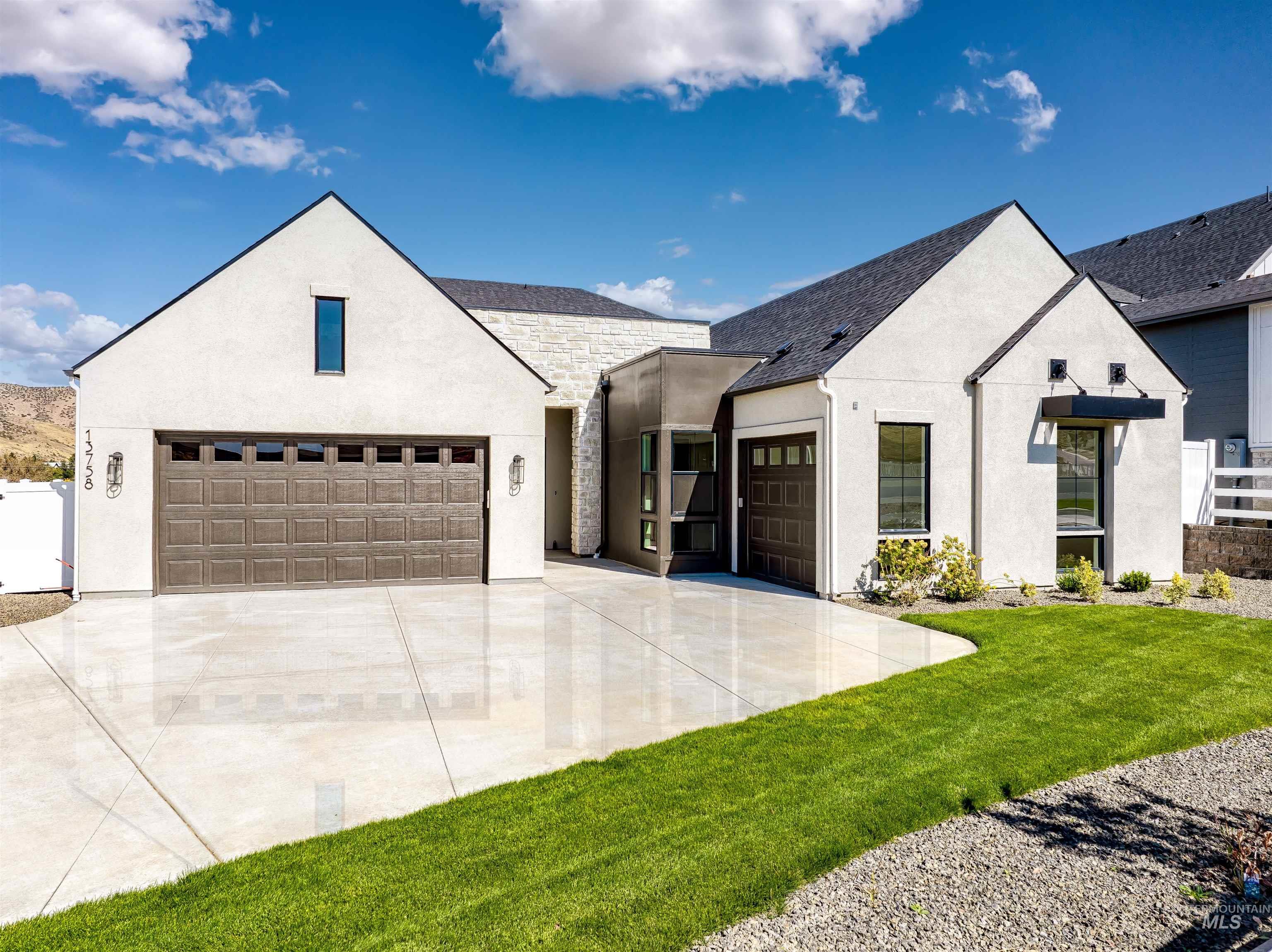 Modern inspired farmhouse with stucco siding, a front lawn, concrete driveway, and a shingled roof