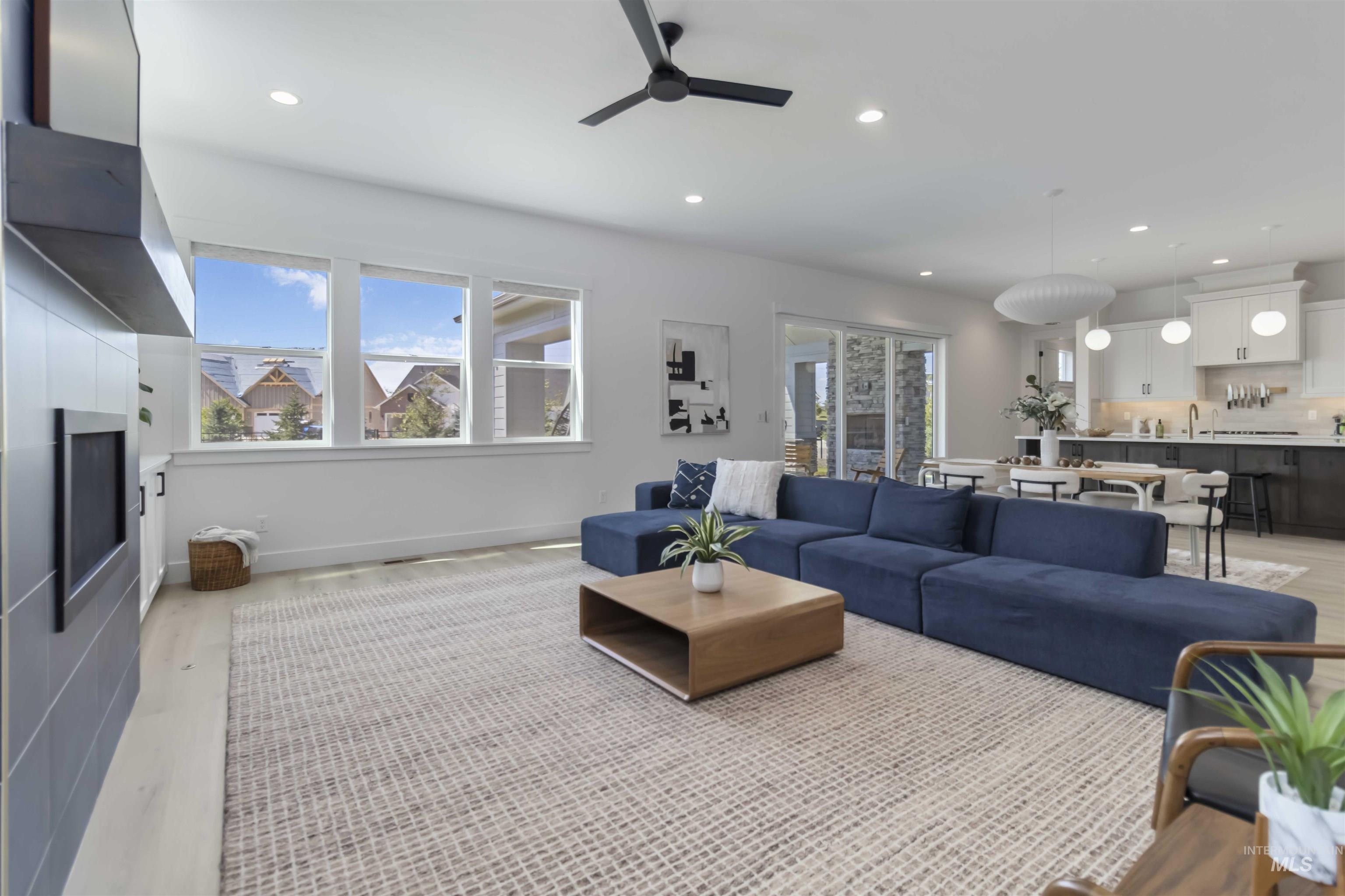 Living room featuring light wood finished floors, recessed lighting, a ceiling fan, and a fireplace