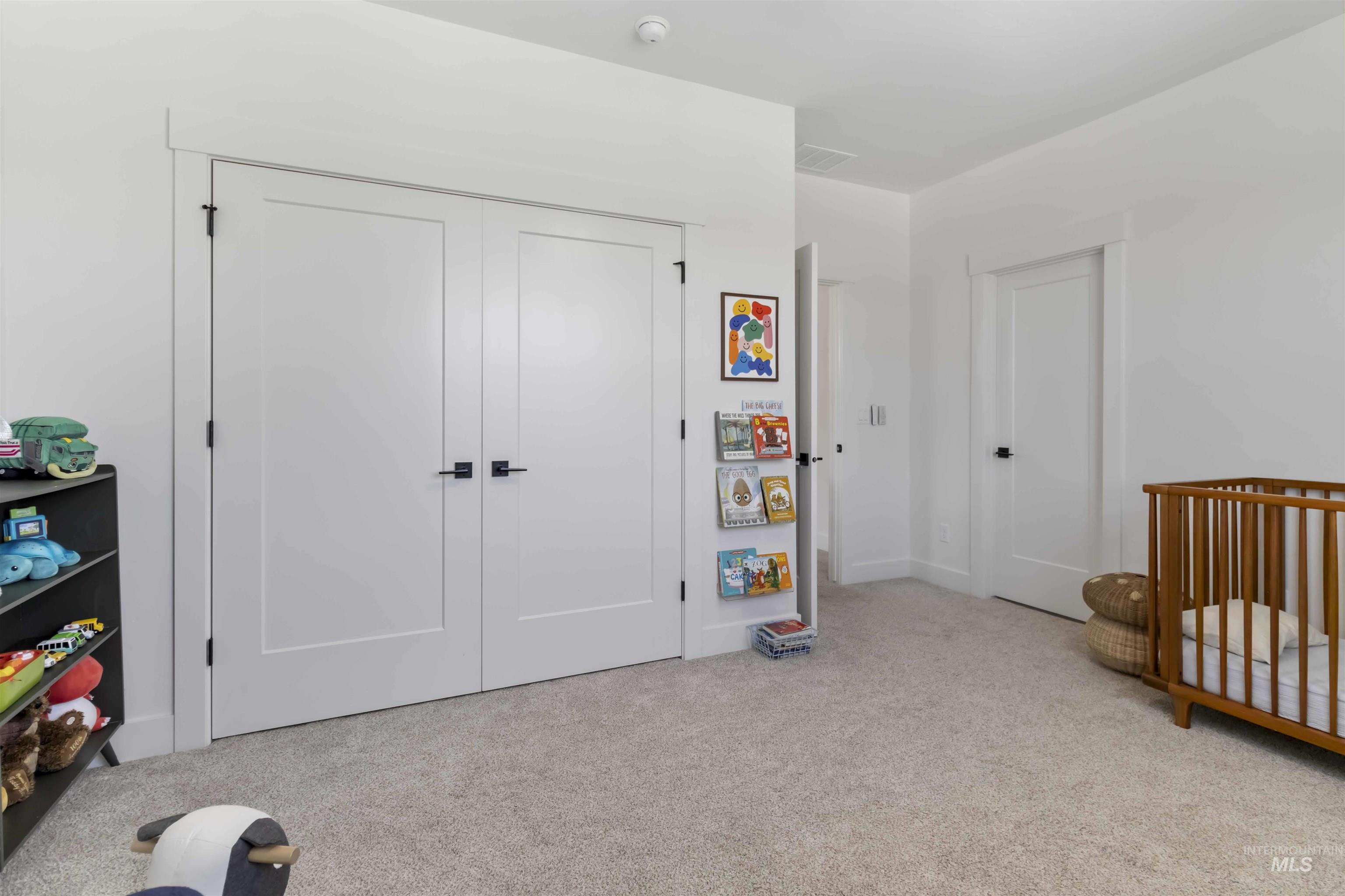 Bedroom with a closet, light carpet, and a crib