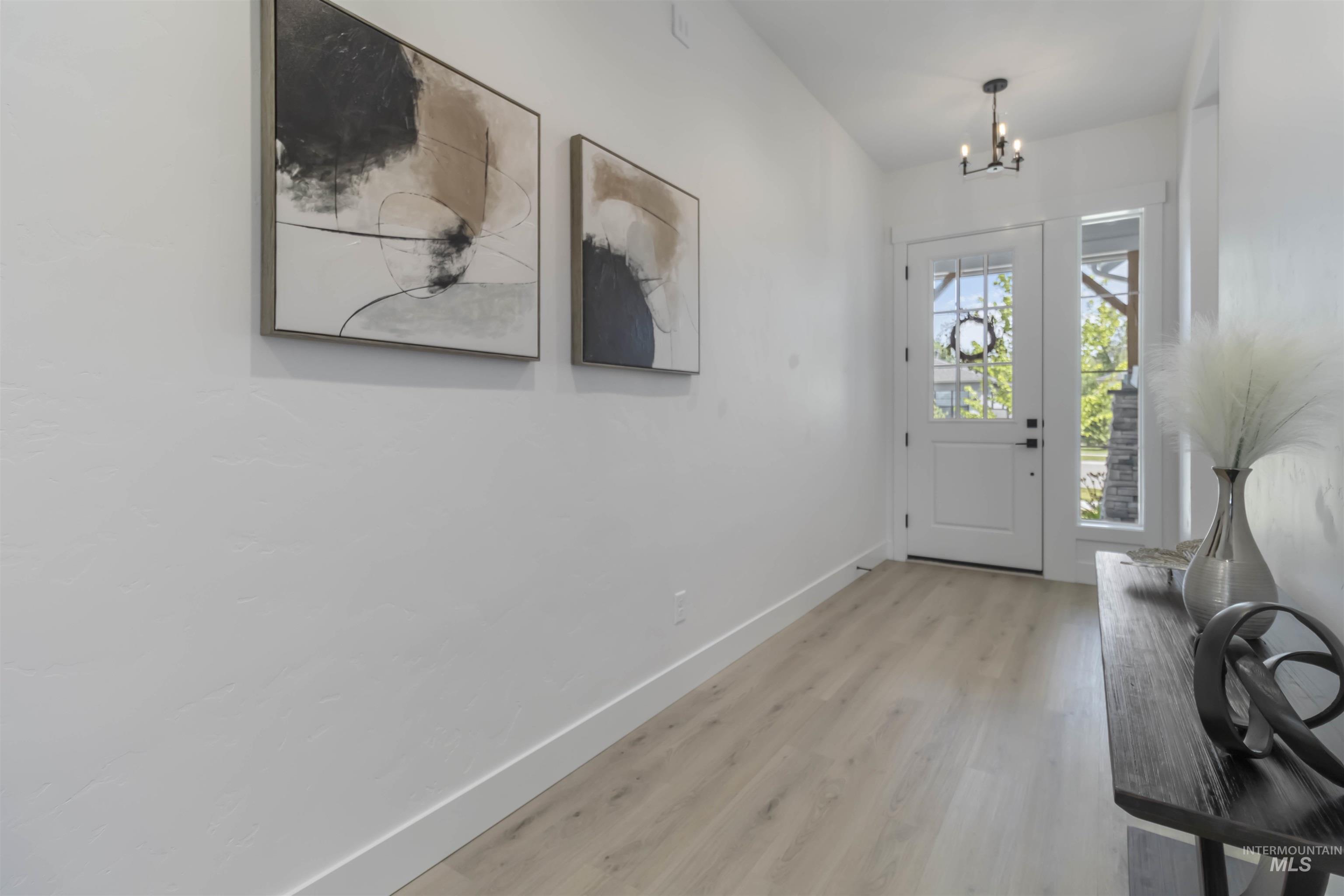 Foyer with suspended lighting and light wood-type flooring