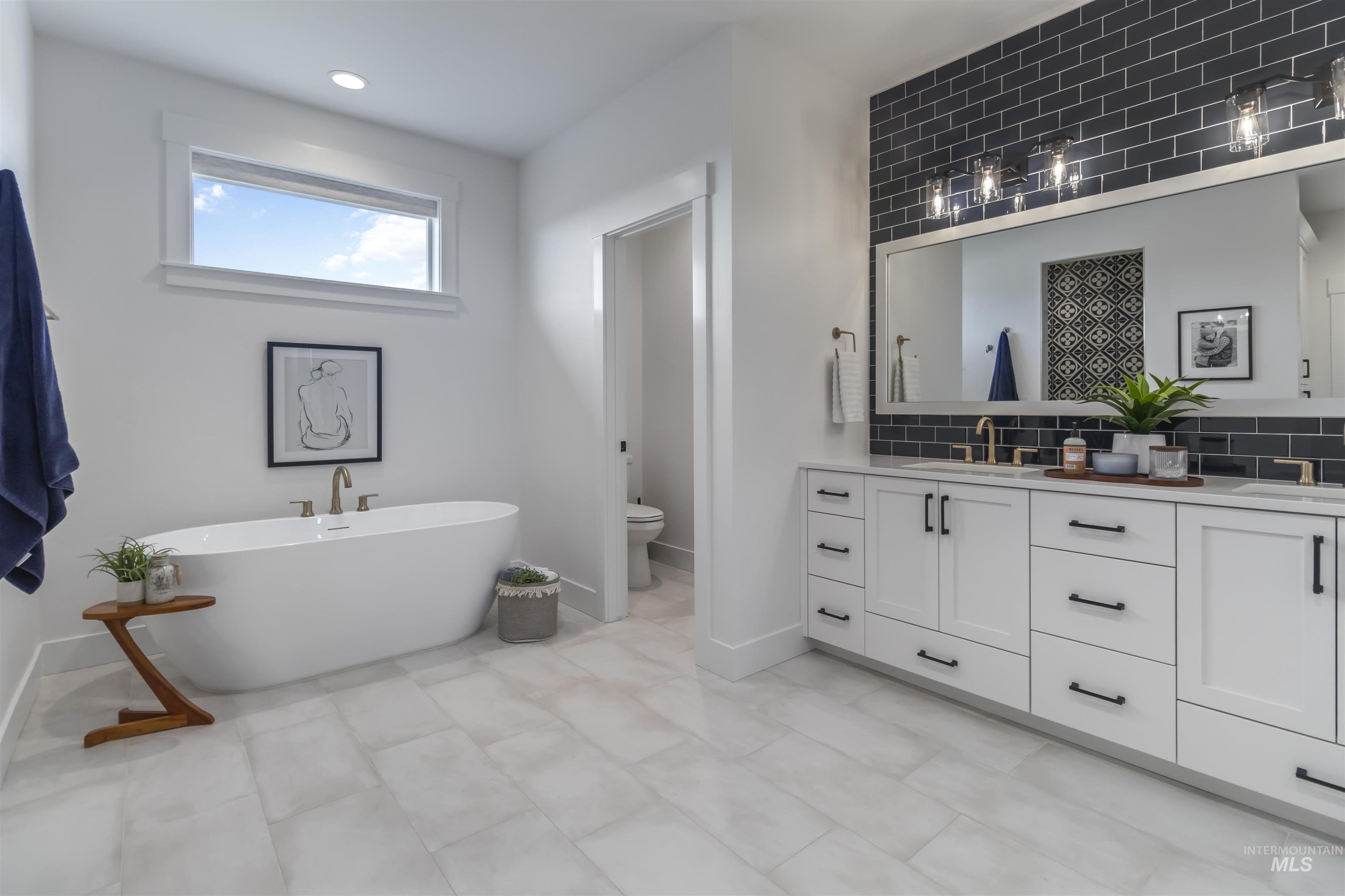 Full bath with double vanity, tasteful backsplash, a soaking tub, and recessed lighting