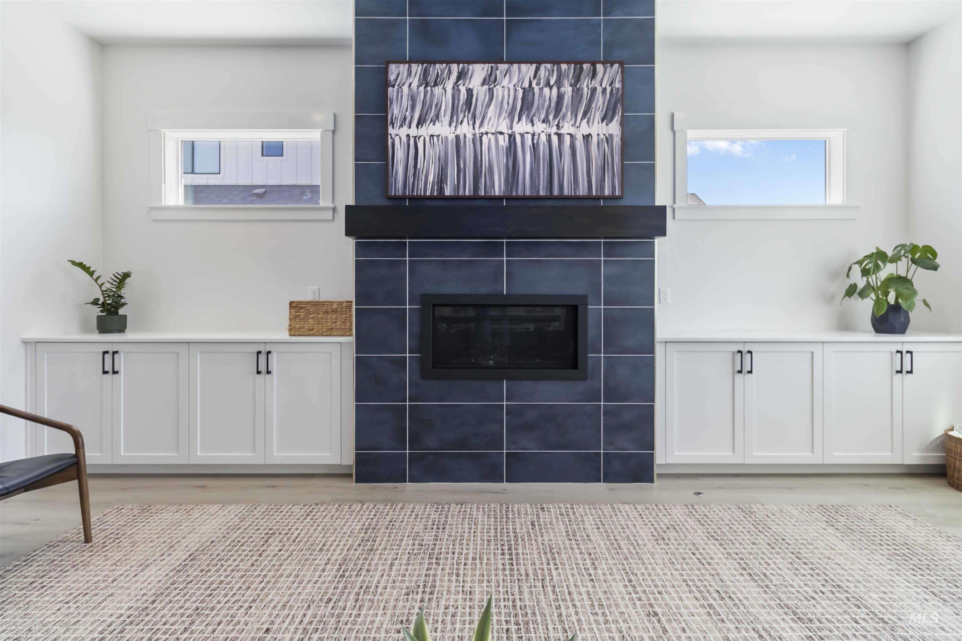 Unfurnished living room featuring a tiled fireplace and wood finished floors