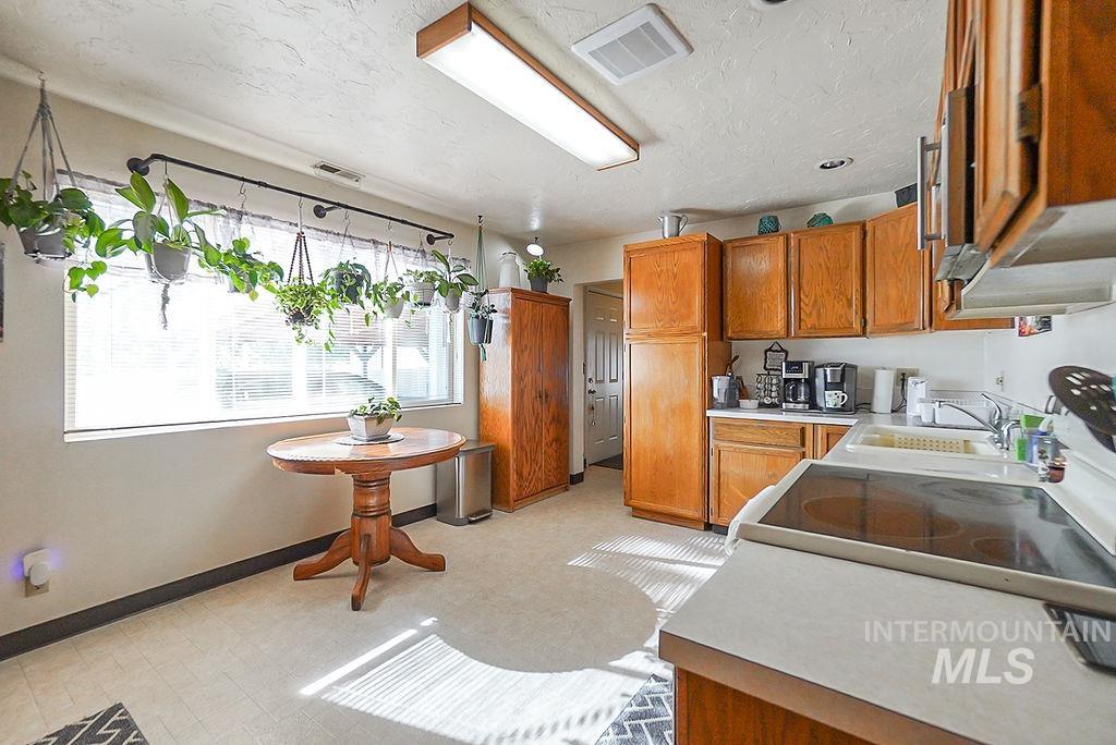 Kitchen featuring light countertops, brown cabinets, a textured ceiling, electric stove, and stainless steel microwave