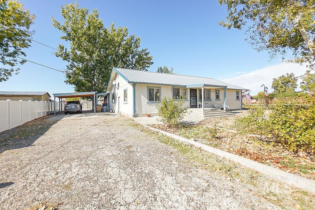 View of front facade featuring a metal roof, driveway, and a porch