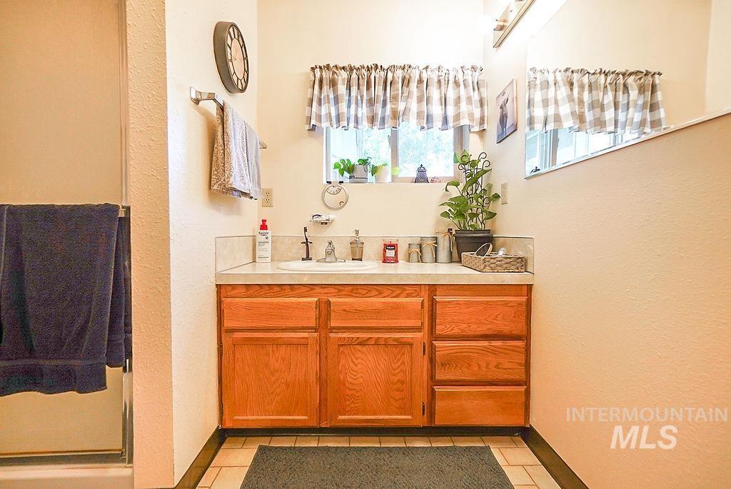 Bathroom featuring vanity, a textured wall, light tile patterned floors, and a shower stall