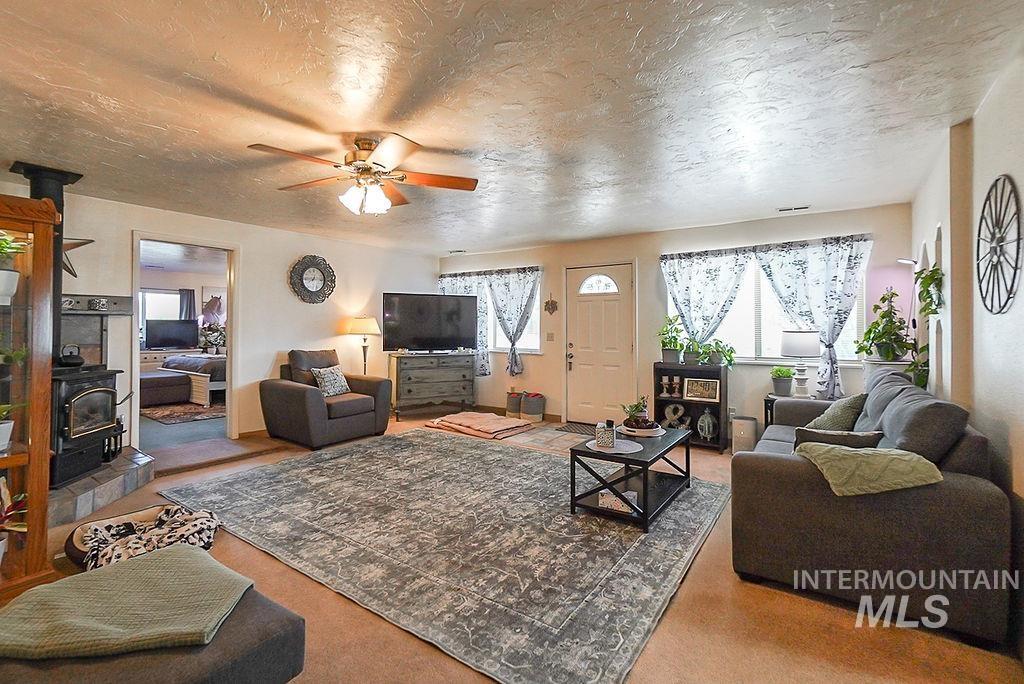Living room with a wood stove, a textured ceiling, and a ceiling fan