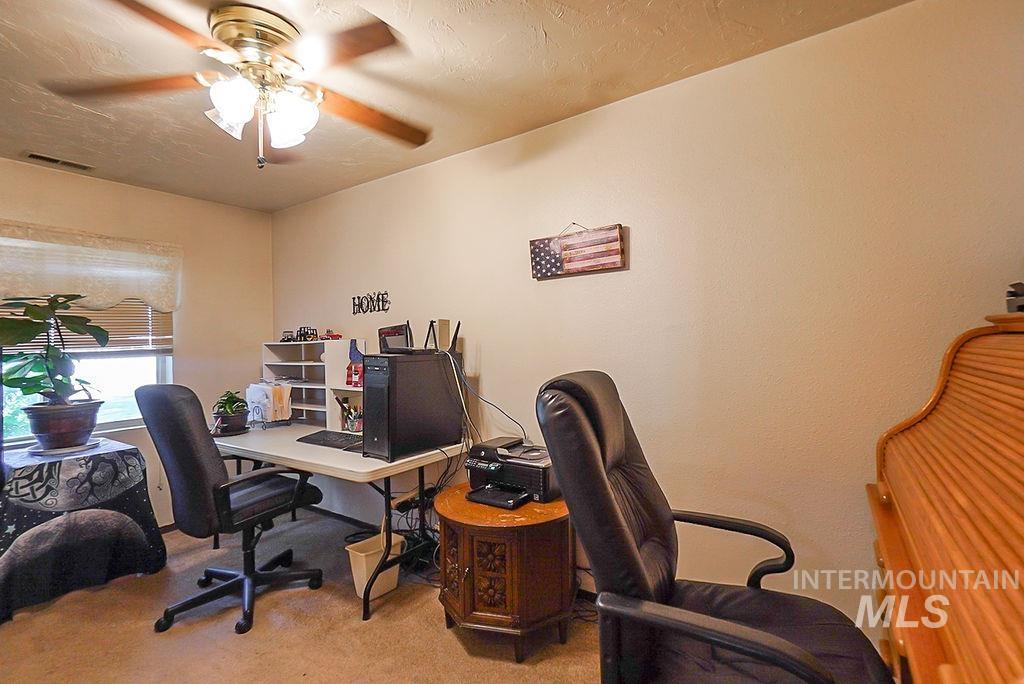 Office space with light colored carpet, a ceiling fan, and a textured ceiling