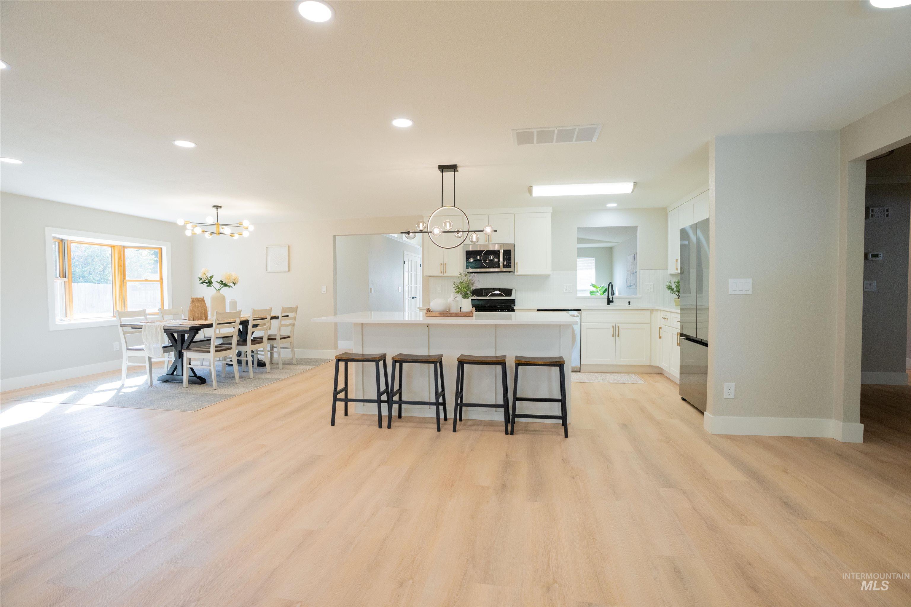 Kitchen with white cabinetry, a kitchen island, recessed lighting, a breakfast bar area, and light wood-style floors