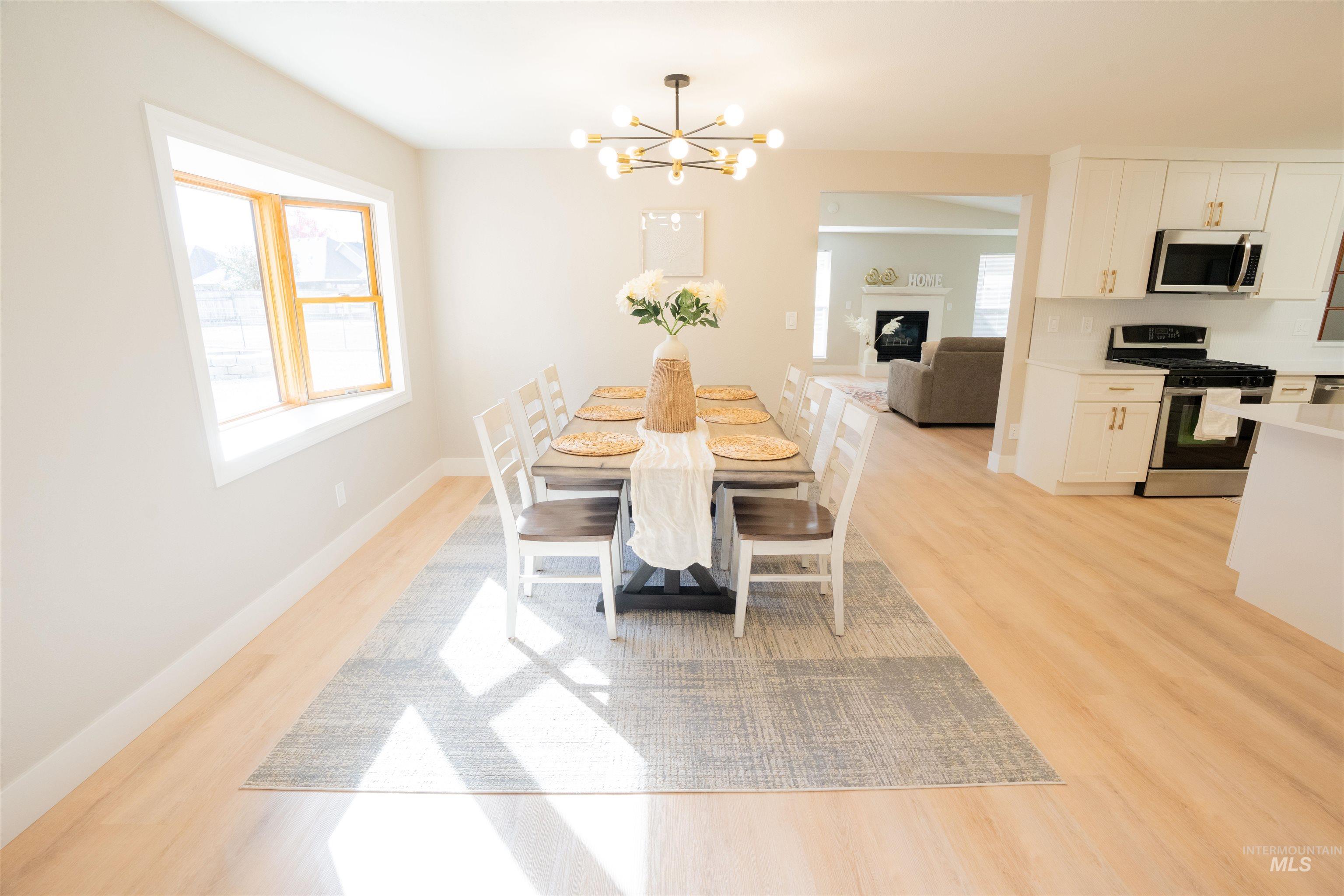 Dining room featuring light wood-type flooring, a fireplace, and a chandelier