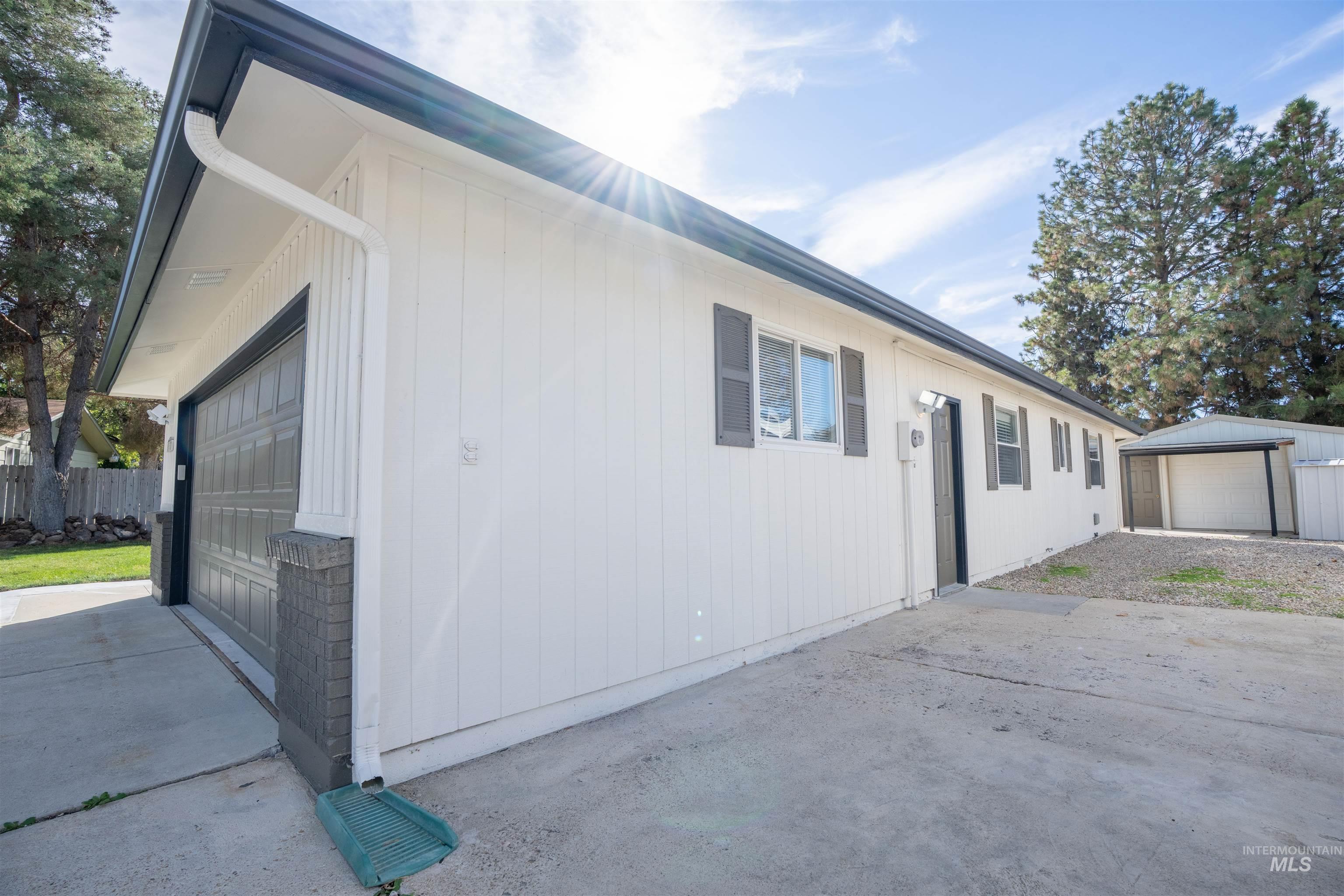 View of side of home with a garage, an outbuilding, and driveway