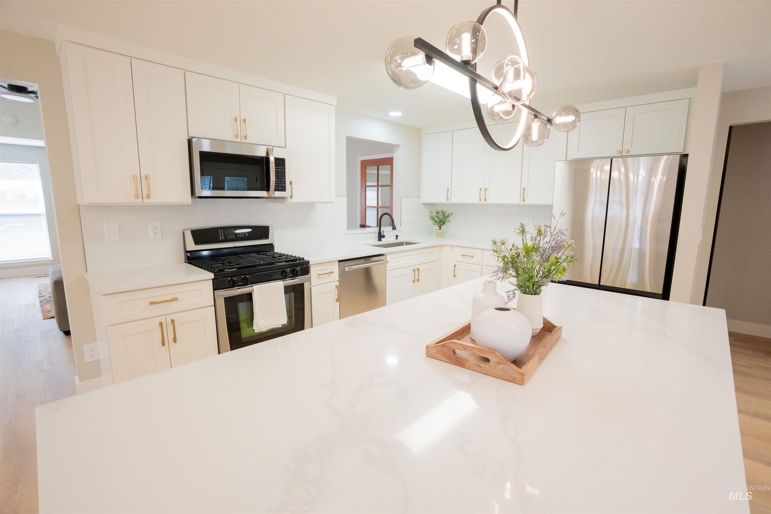 Kitchen featuring light wood-style floors, appliances with stainless steel finishes, light stone counters, and recessed lighting