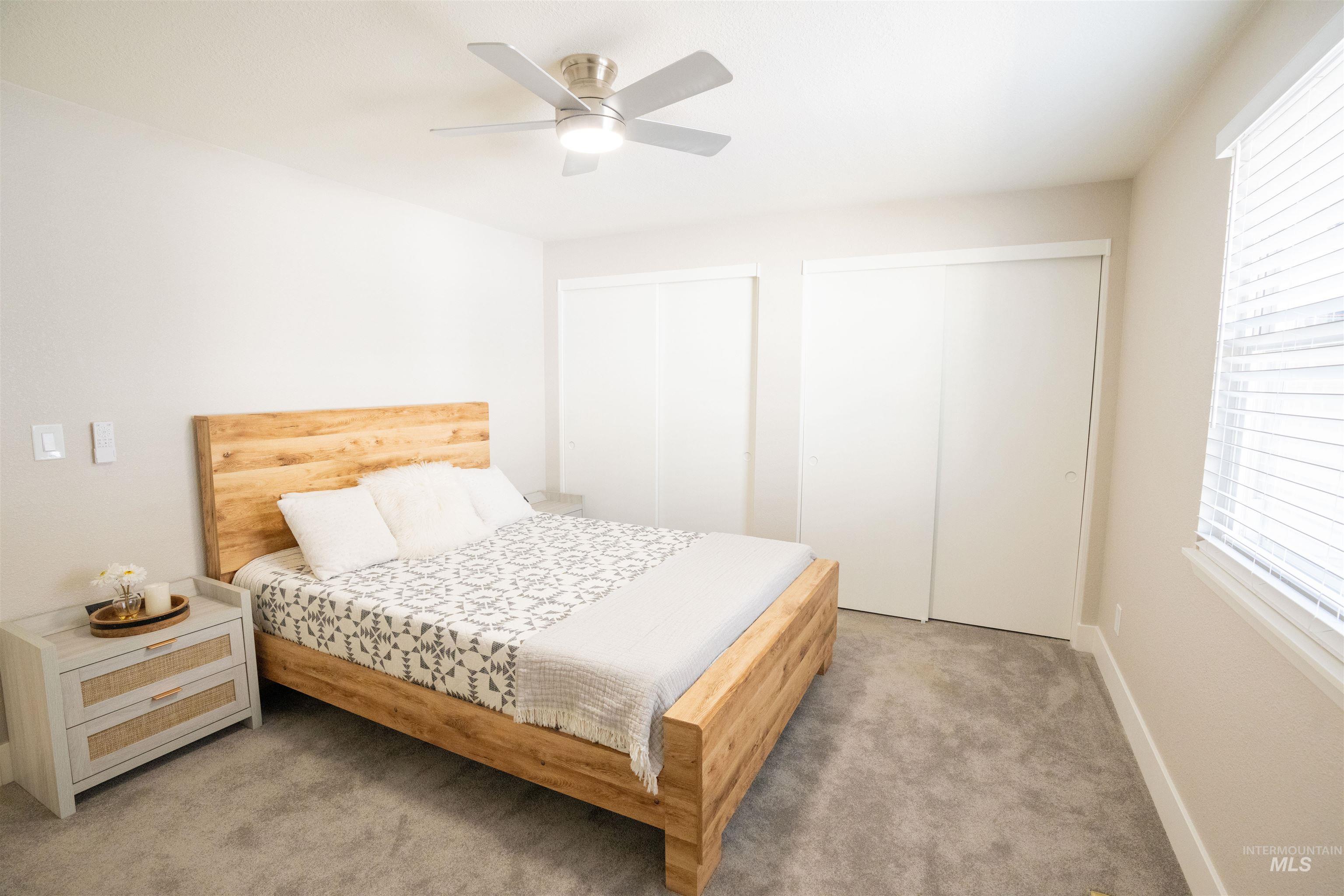 Bedroom with two closets, carpet flooring, and ceiling fan