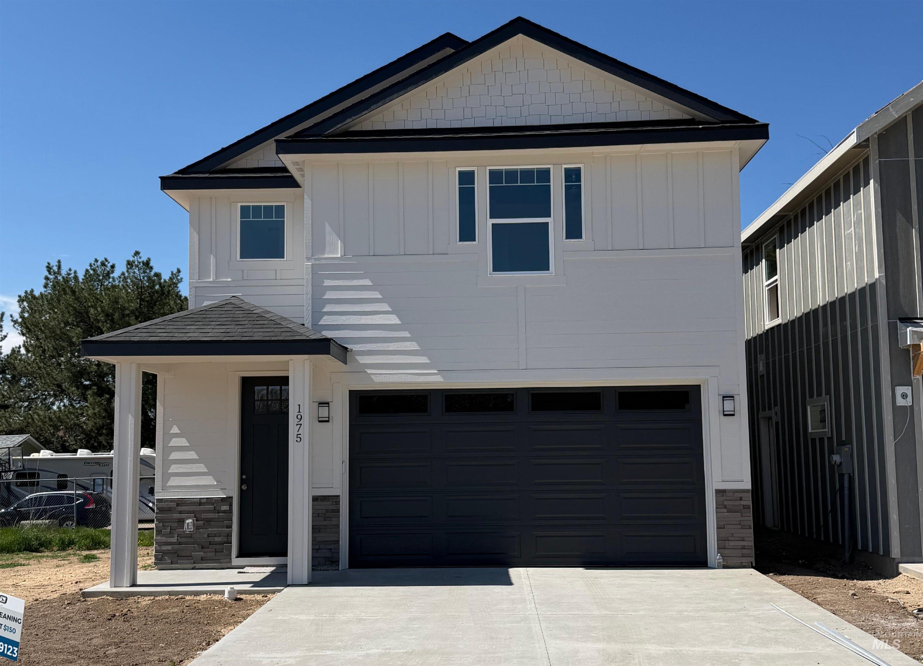 View of front of home featuring an attached garage, board and batten siding, concrete driveway, and stone siding