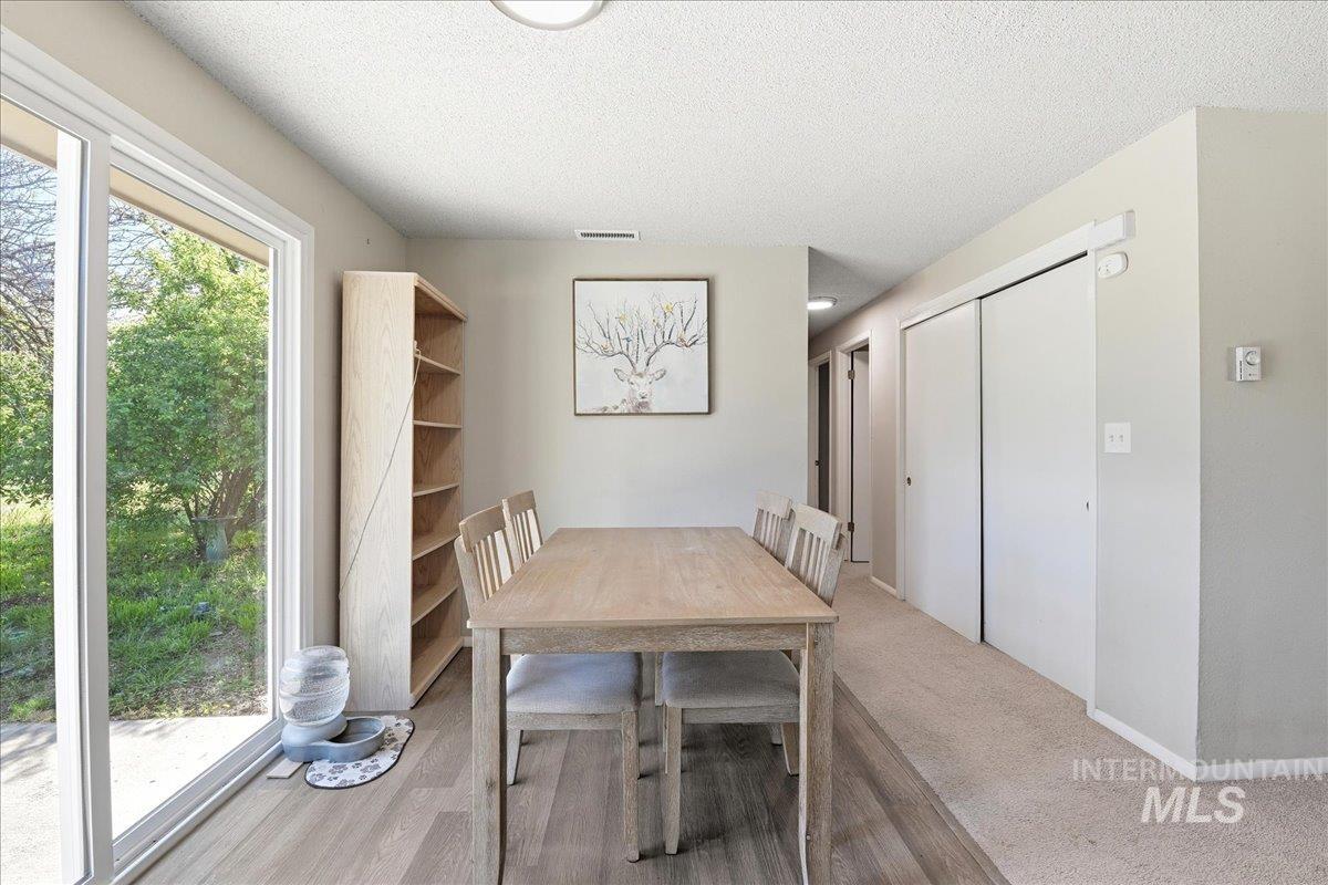 Dining area featuring wood-finish flooring, sliding glass doors to exterior, and neutral wall tones