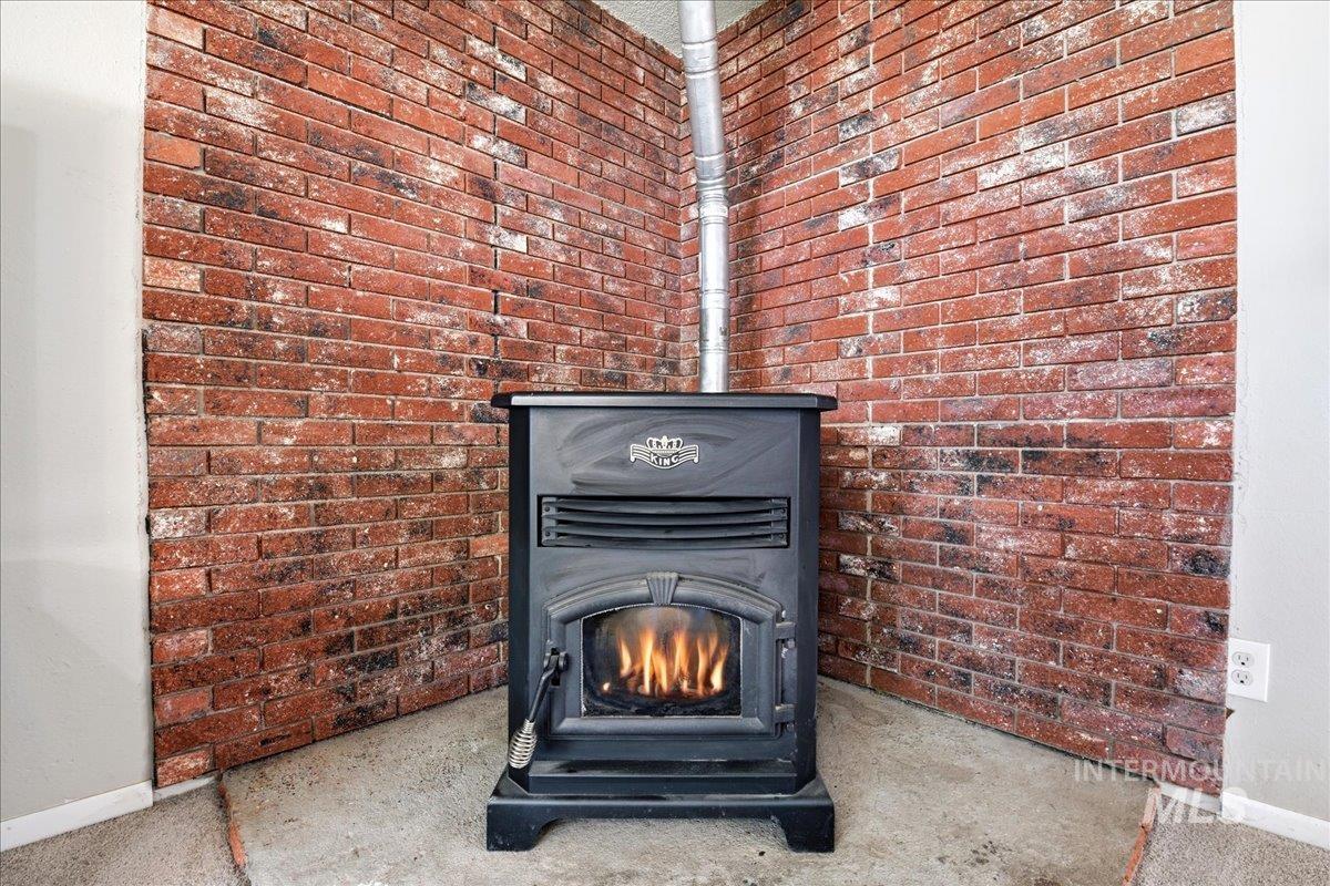 Corner pellet stove with visible flame, set against an exposed brick accent wall