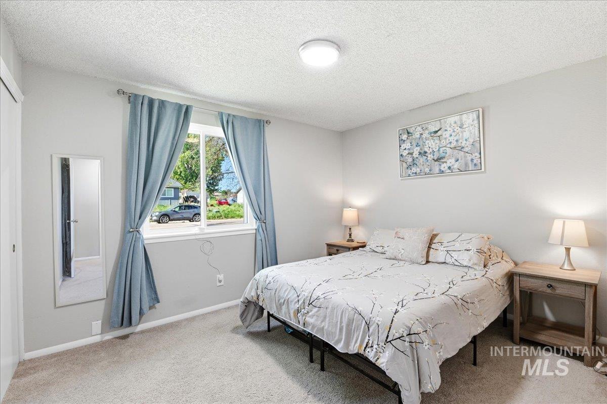 Bedroom featuring neutral-toned carpeting, light gray walls, and a white trim baseboard