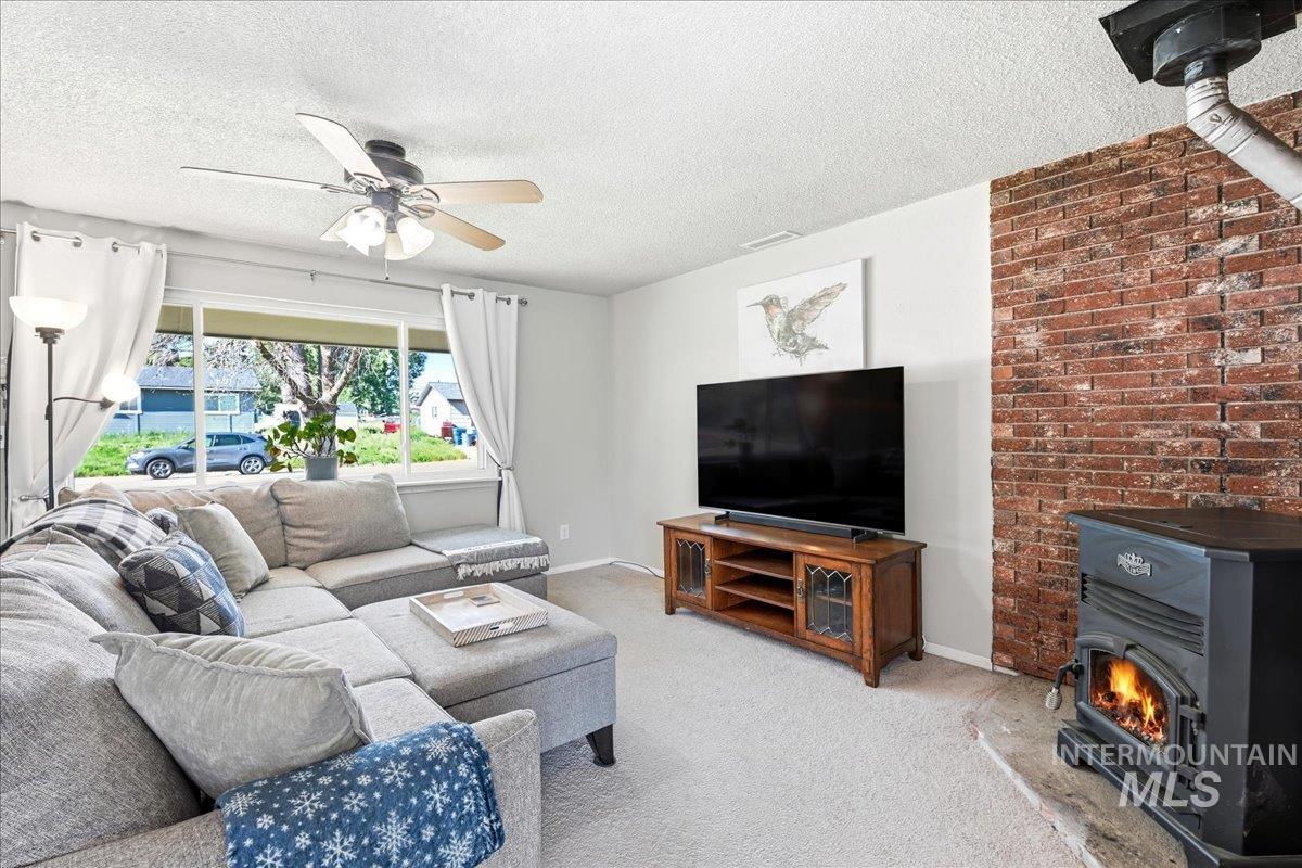 Living area featuring a floor-to-ceiling exposed brick accent wall, a wood-burning stove with a visible firebox, and a large window