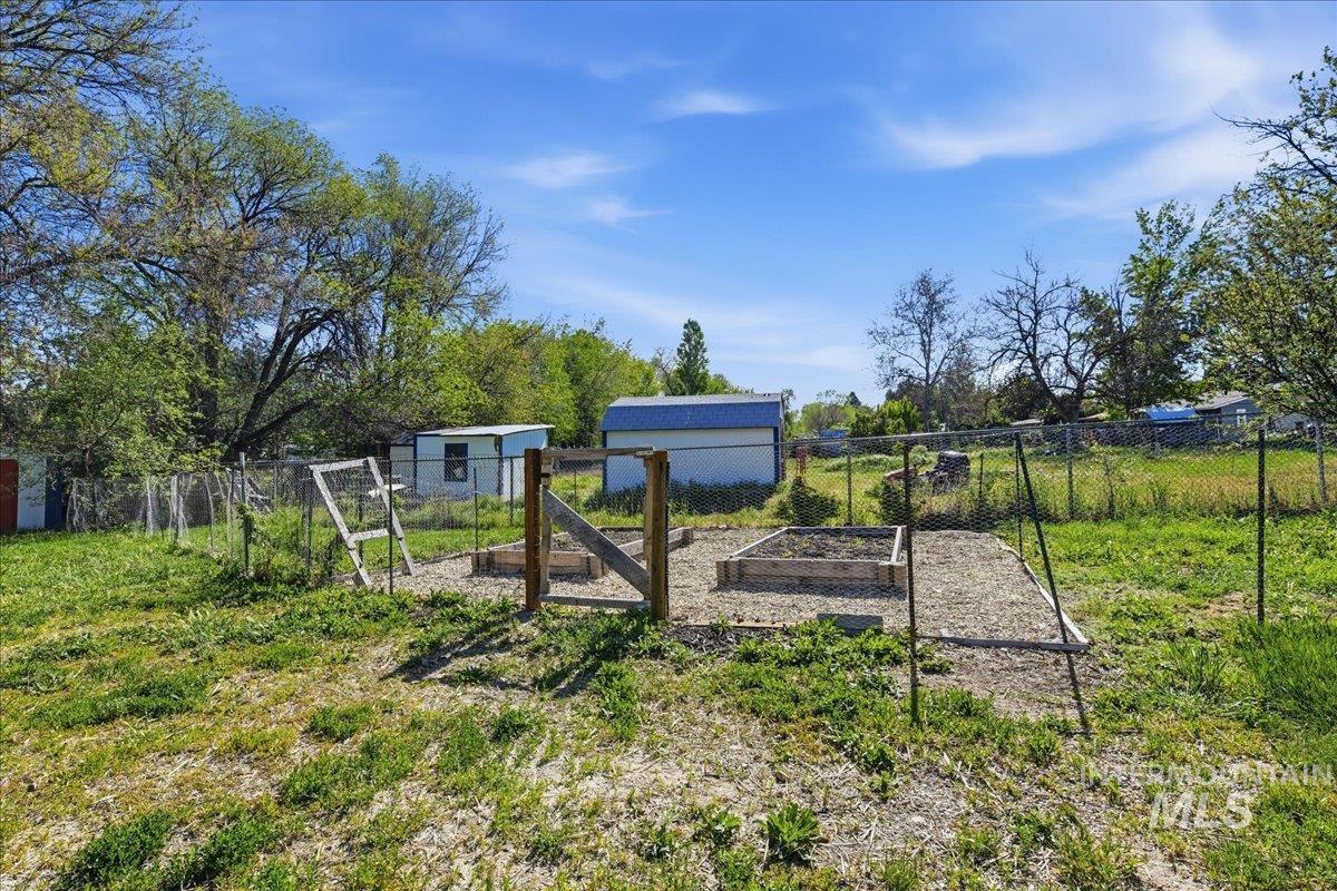 Expansive outdoor area featuring two raised garden beds, a fenced perimeter, and ample green space