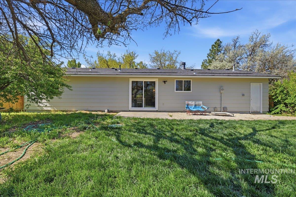Expansive backyard featuring a lush lawn, concrete patio, and mature trees