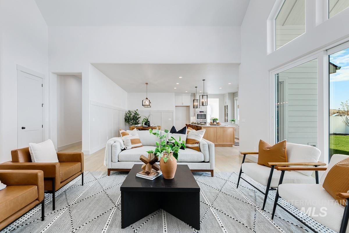 Living room featuring a towering ceiling, light wood-style floors, and recessed lighting