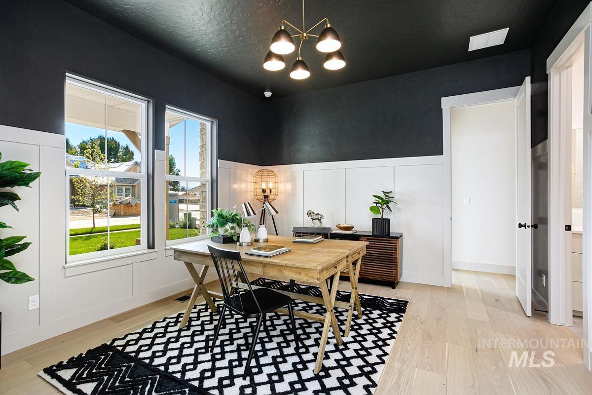 Office featuring a decorative wall, light wood-style flooring, a chandelier, wainscoting, and a textured ceiling