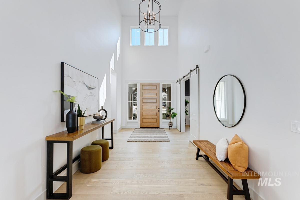 Entrance foyer featuring a barn door, light wood finished floors, and a towering ceiling