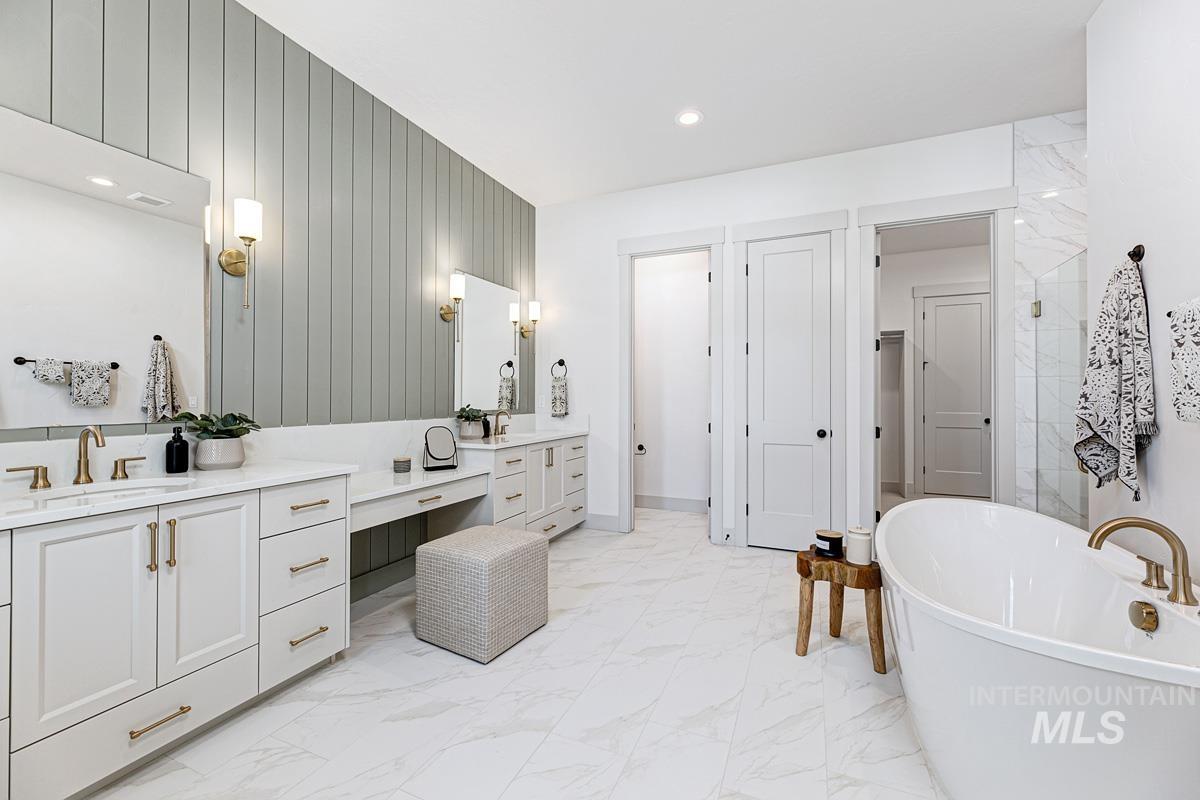 Full bathroom featuring a freestanding tub, light marble finish flooring, vanity, and recessed lighting