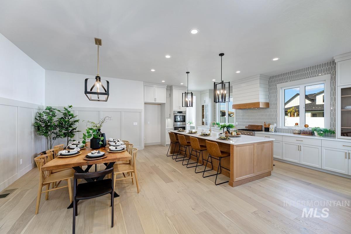 Kitchen with white cabinetry, a decorative wall, a wainscoted wall, a kitchen island, and decorative light fixtures