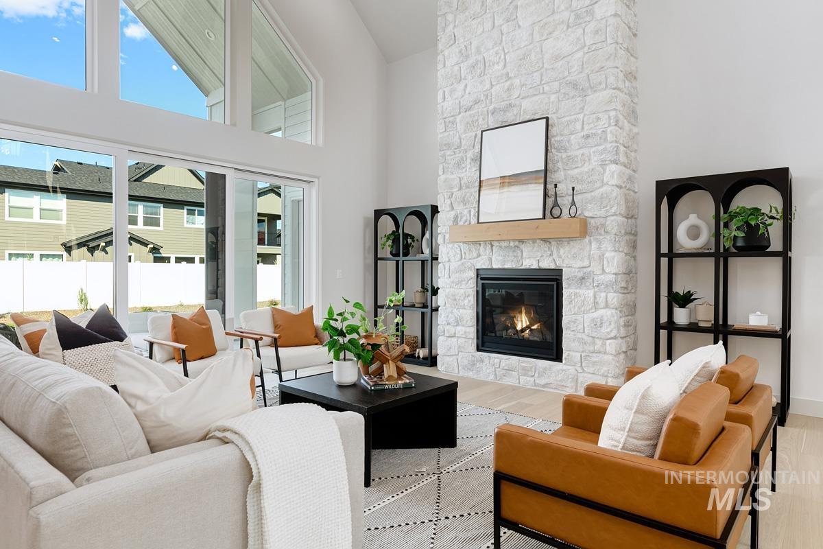 Living area featuring a towering ceiling, a fireplace, and wood finished floors