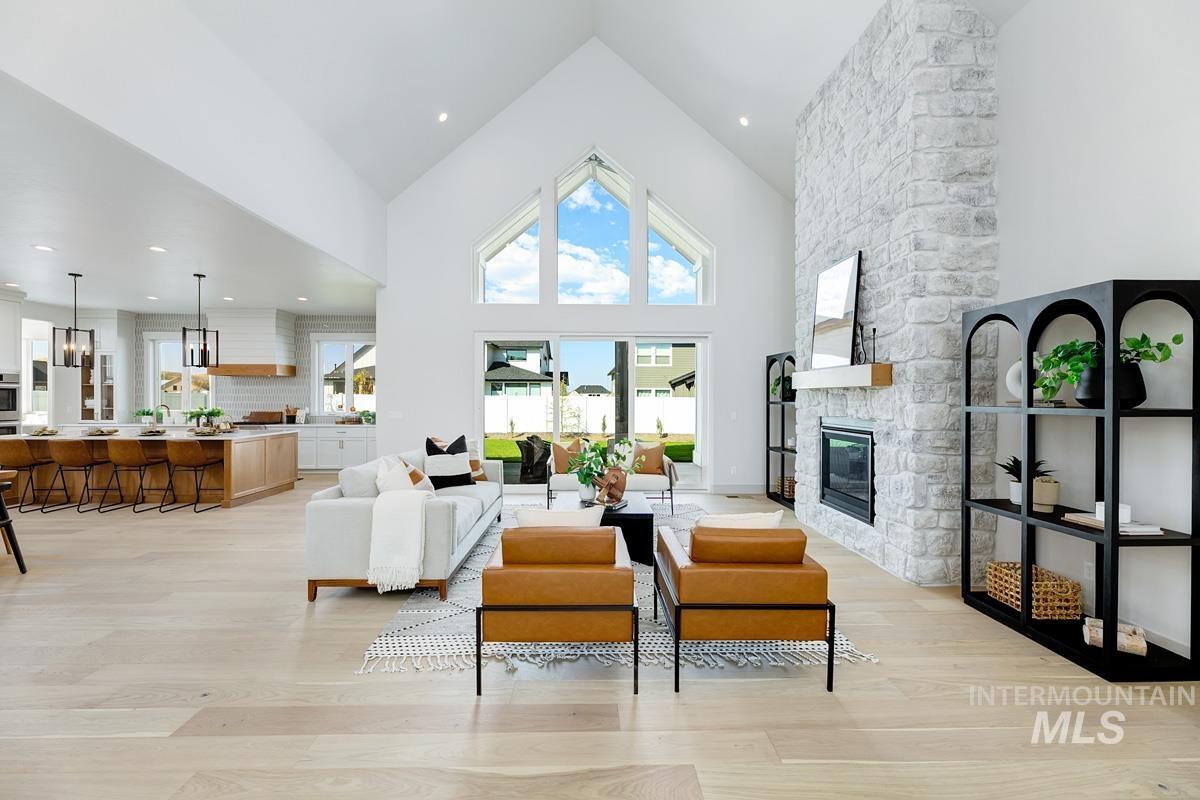 Living room with high vaulted ceiling, light wood finished floors, a fireplace, and recessed lighting