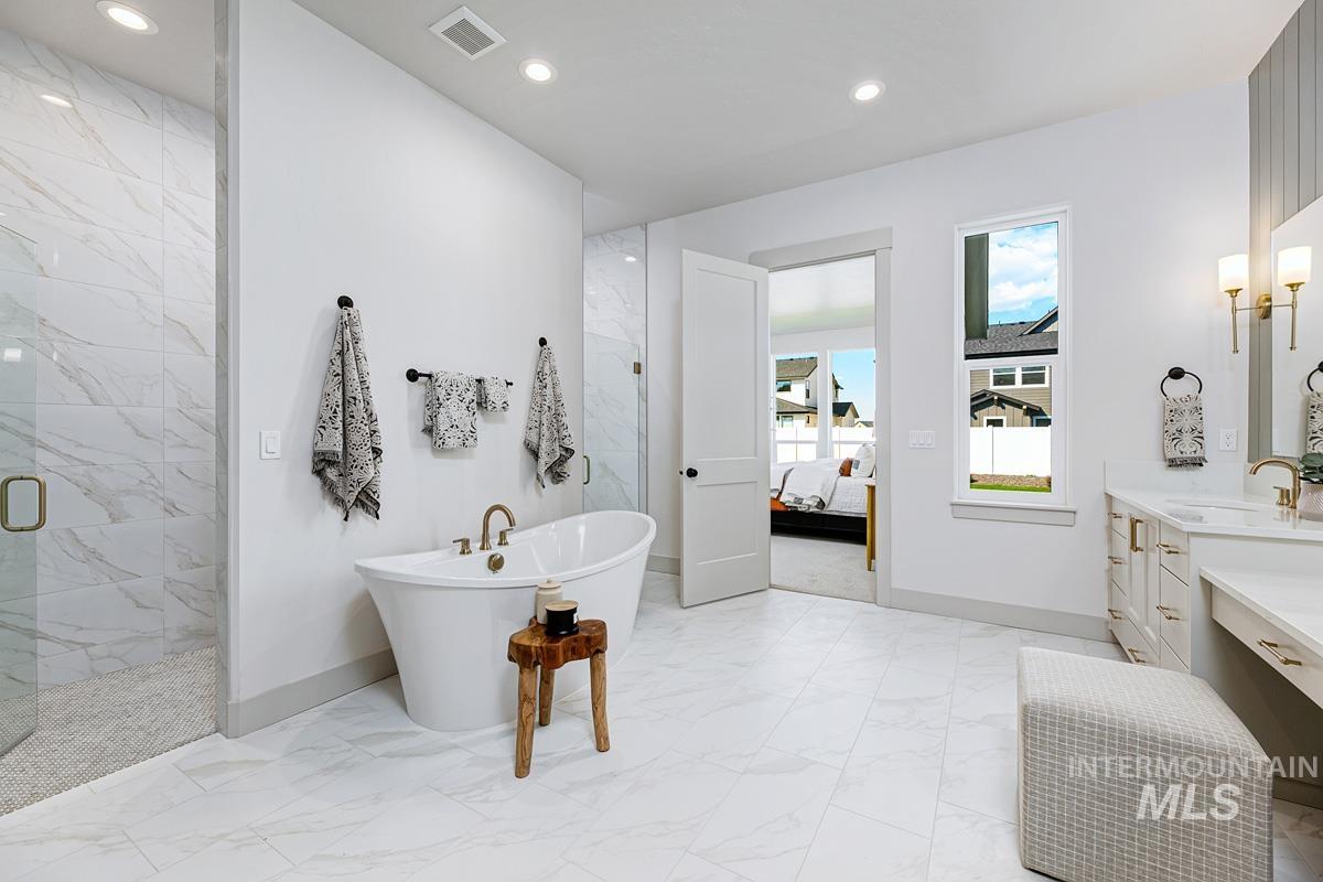 Full bath with vanity, a marble finish shower, connected bathroom, a freestanding bath, and recessed lighting