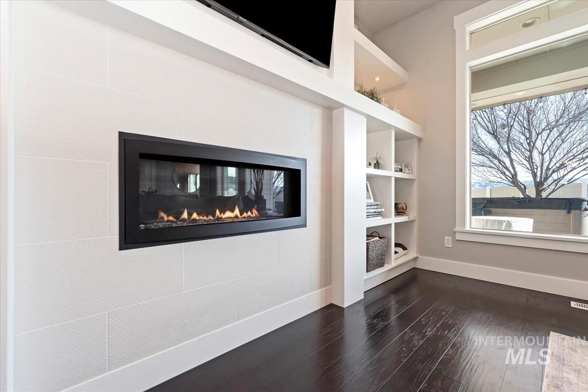 Detailed view of wood finished floors, a fireplace, and built in shelves