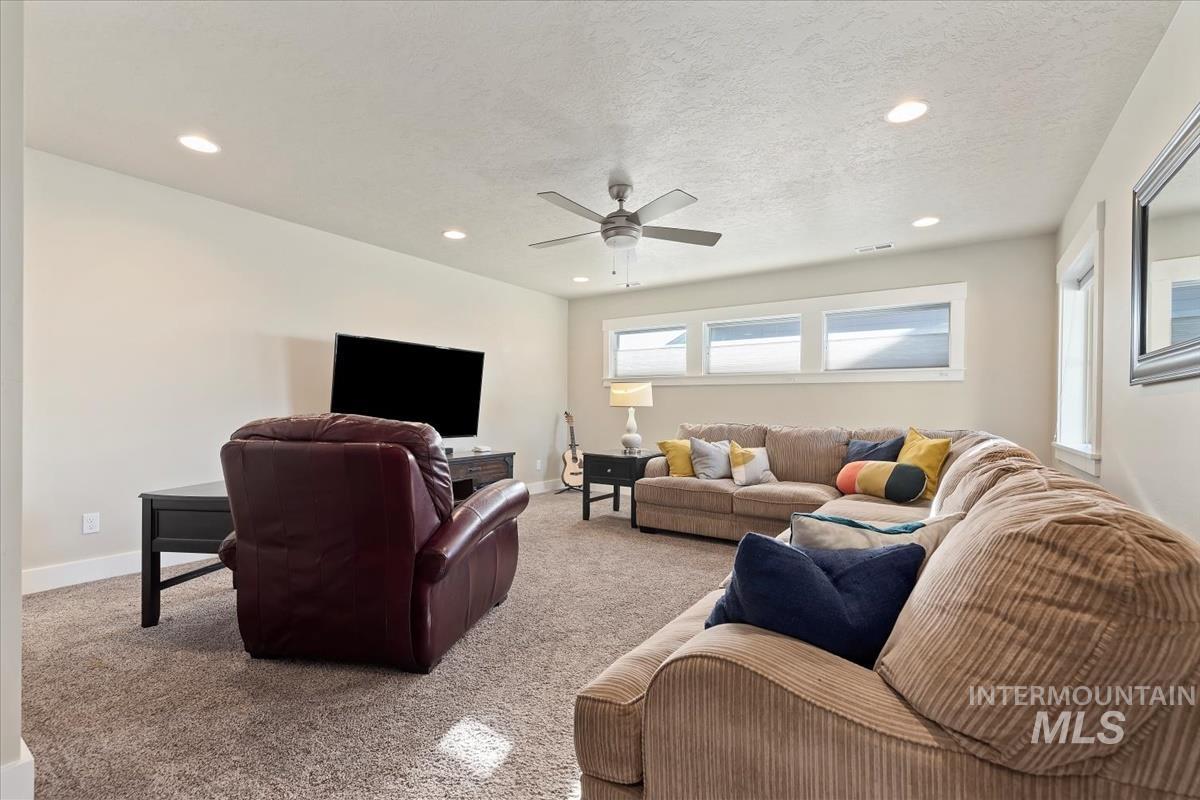 Carpeted living area with recessed lighting, ceiling fan, and a textured ceiling