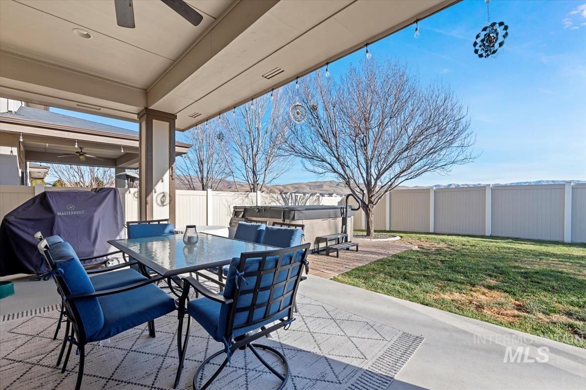 Fenced backyard featuring ceiling fan, a patio area, a grill, and a hot tub