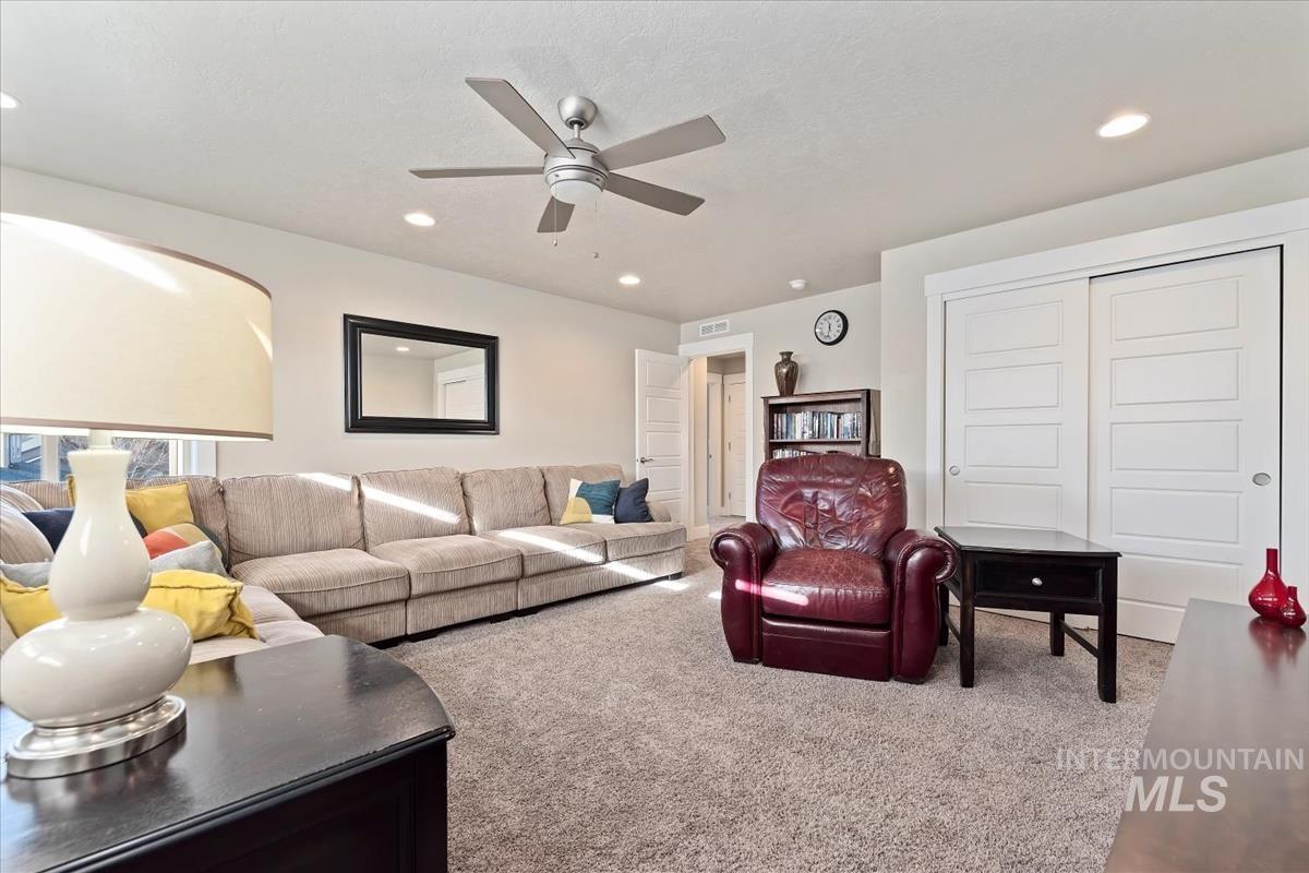Carpeted living area with recessed lighting and a ceiling fan