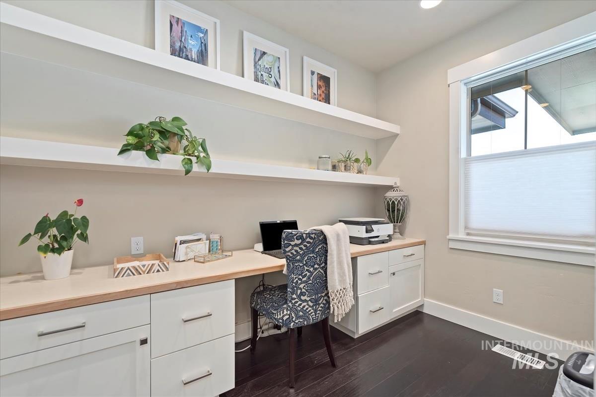 Office featuring built in desk and dark wood-type flooring