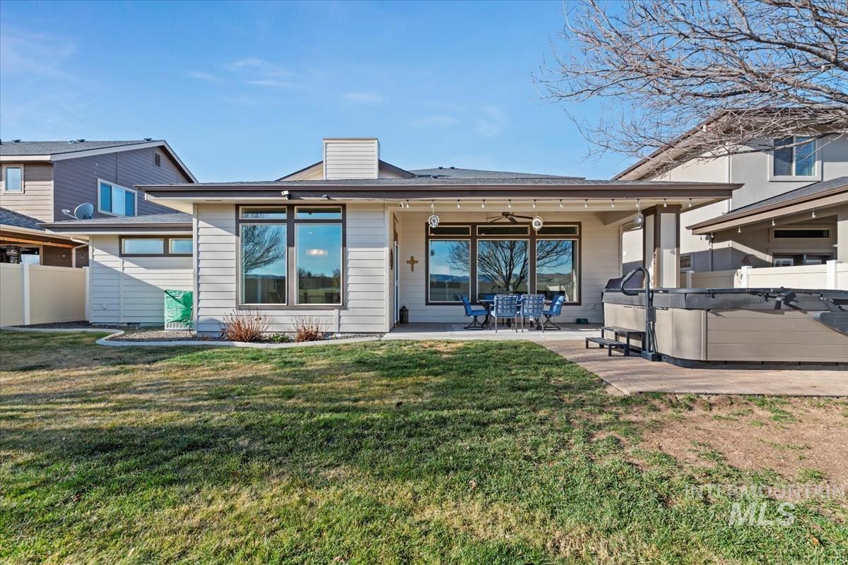 Rear view of property with a hot tub, a patio, a ceiling fan, and a chimney