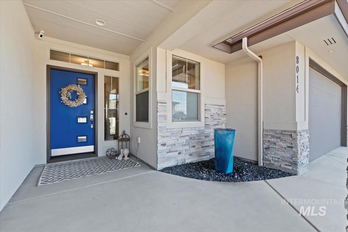 Property entrance featuring stone siding, stucco siding, and a garage